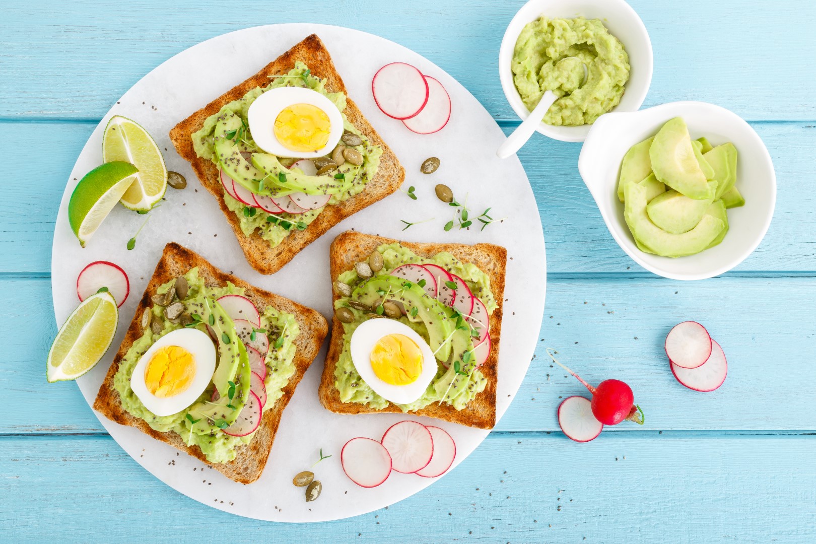 Toasts with avocado guacamole, fresh radish, boiled egg, chia and pumpkin seeds. Diet breakfast. Delicious and healthy plant-based food. Flat lay. Top view
